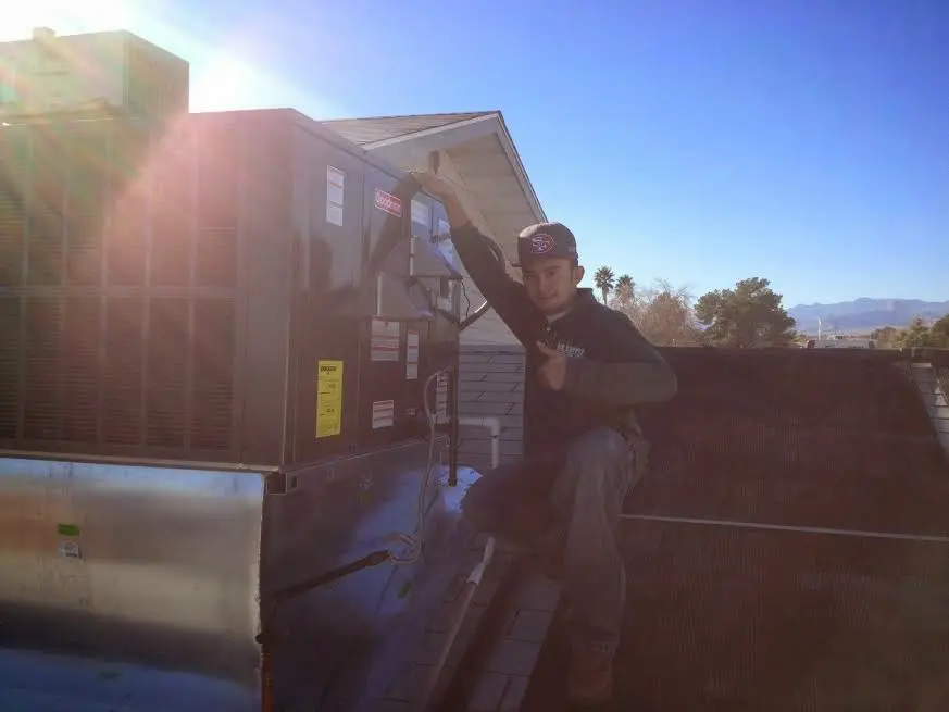 HVAC technician performing AC Tune-Up on a rooftop unit in Sugar Hill